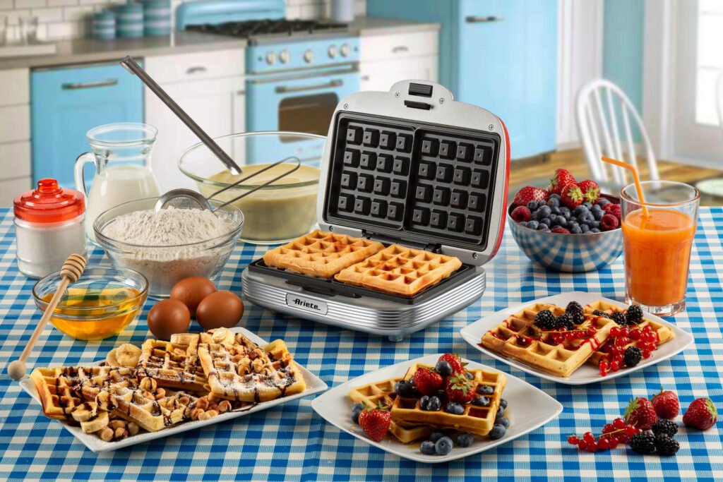 A imagem mostra a máquina de waffle Retrô Party Time em uma mesa montada com vários ingredientes para waffle. E também alguns pratos com waffles prontos com recheios.